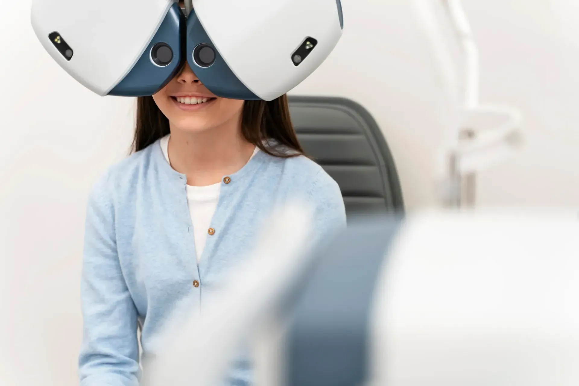 A person wearing a phoropter device during an eye examination in a clinical office setting.
