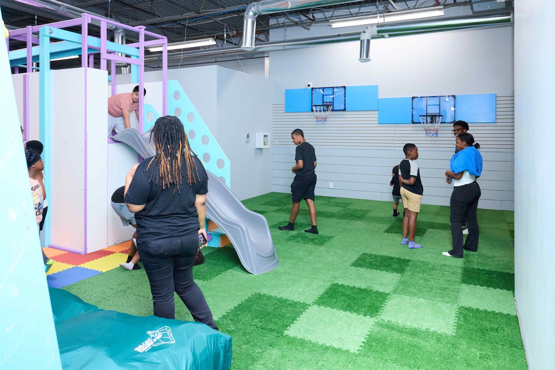 Children playing in a colorful indoor playground with a slide and climbing structure