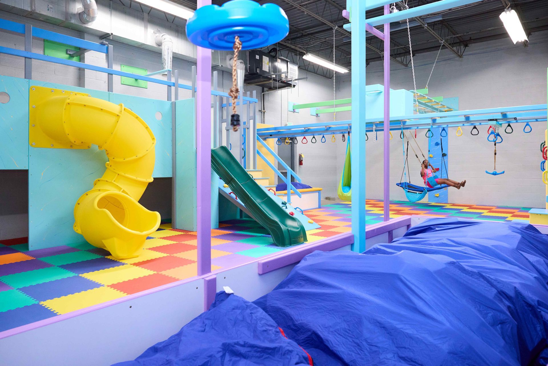 Colorful indoor playground with slides, climbing nets, and padded play area