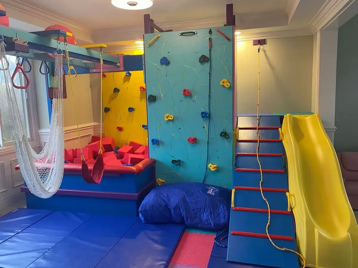 Indoor kids’ play area with colorful climbing walls, slide, and soft mats