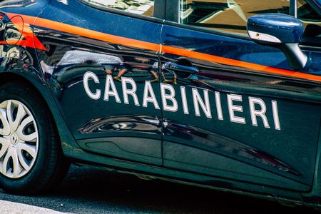Vista laterale di un'auto della polizia dei Carabinieri italiani, di colore blu scuro con striscia arancione e scritte bianche.