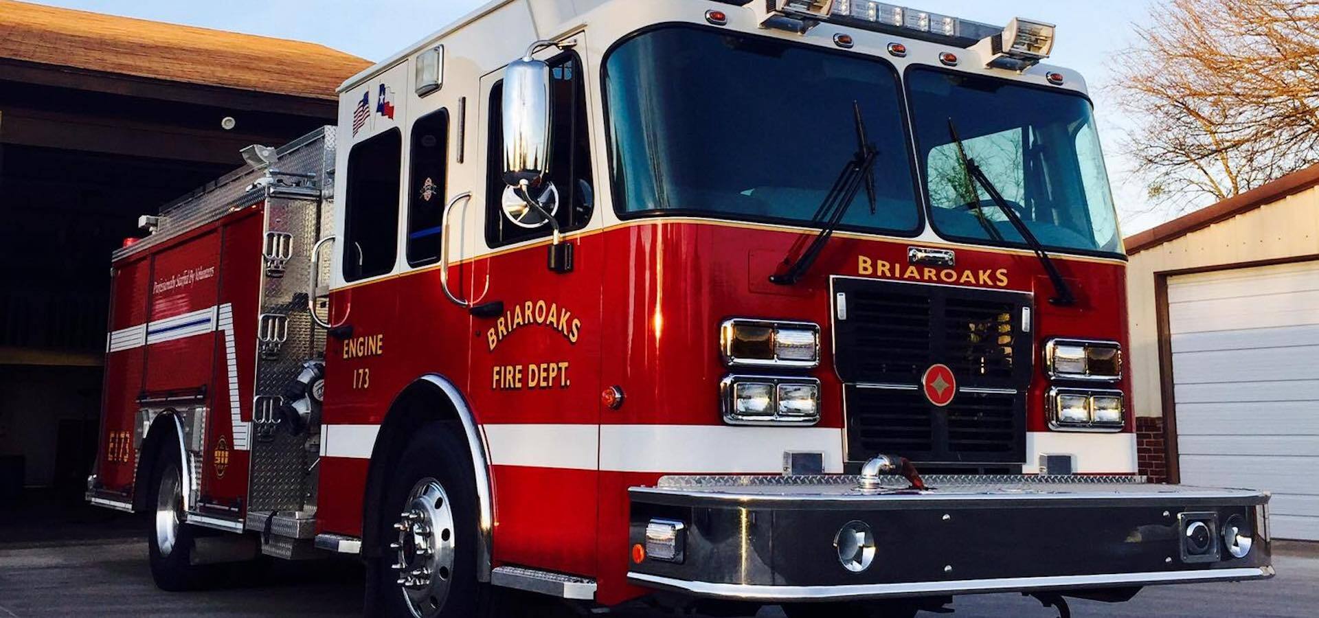 A Briaroaks fire truck is parked in front of a garage