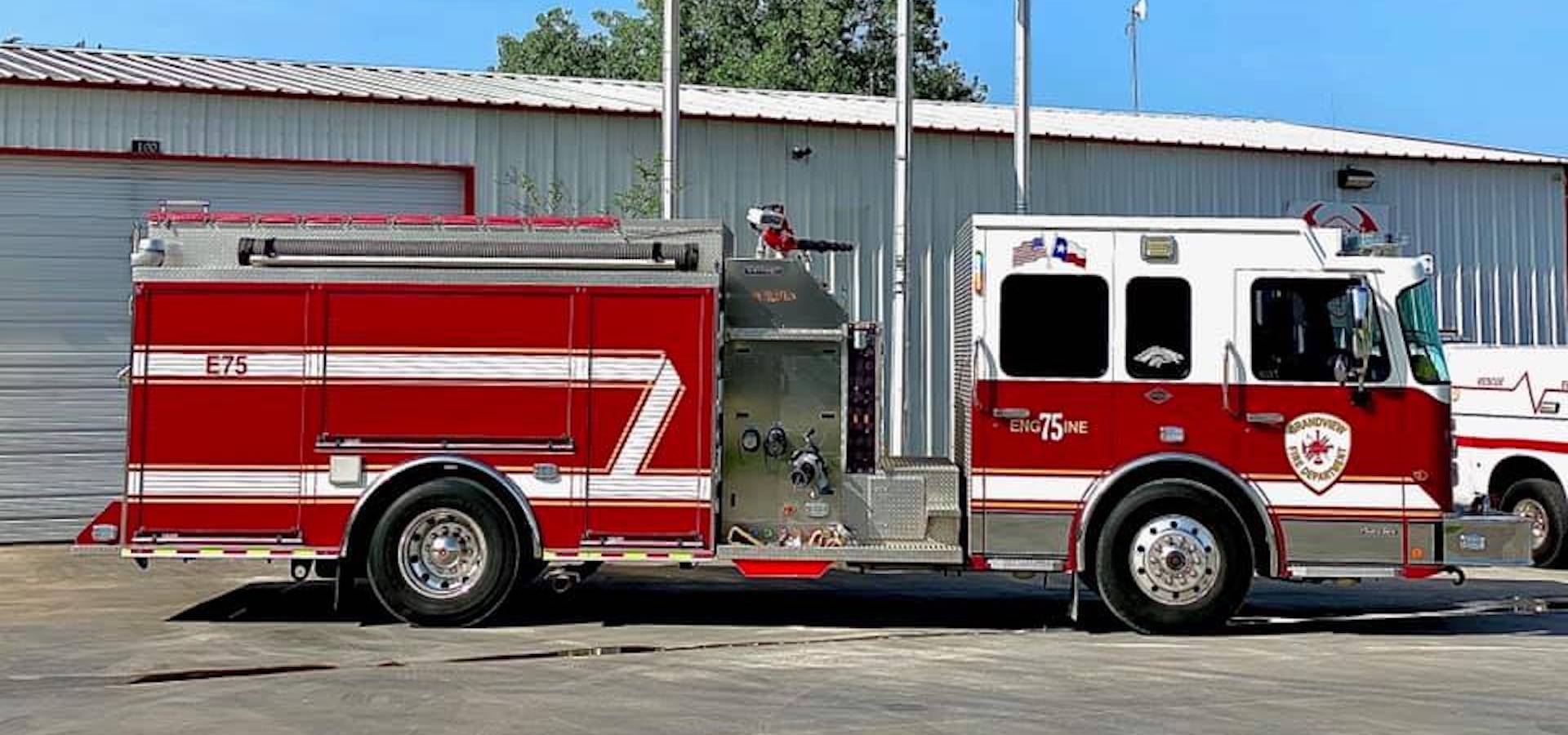 A red and white fire truck is parked in front of a fire station.