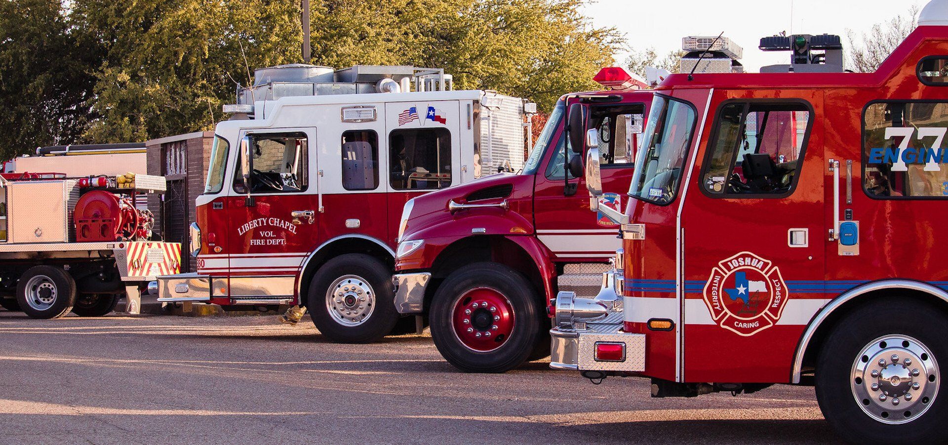 A row of fire trucks are parked on the side of the road.