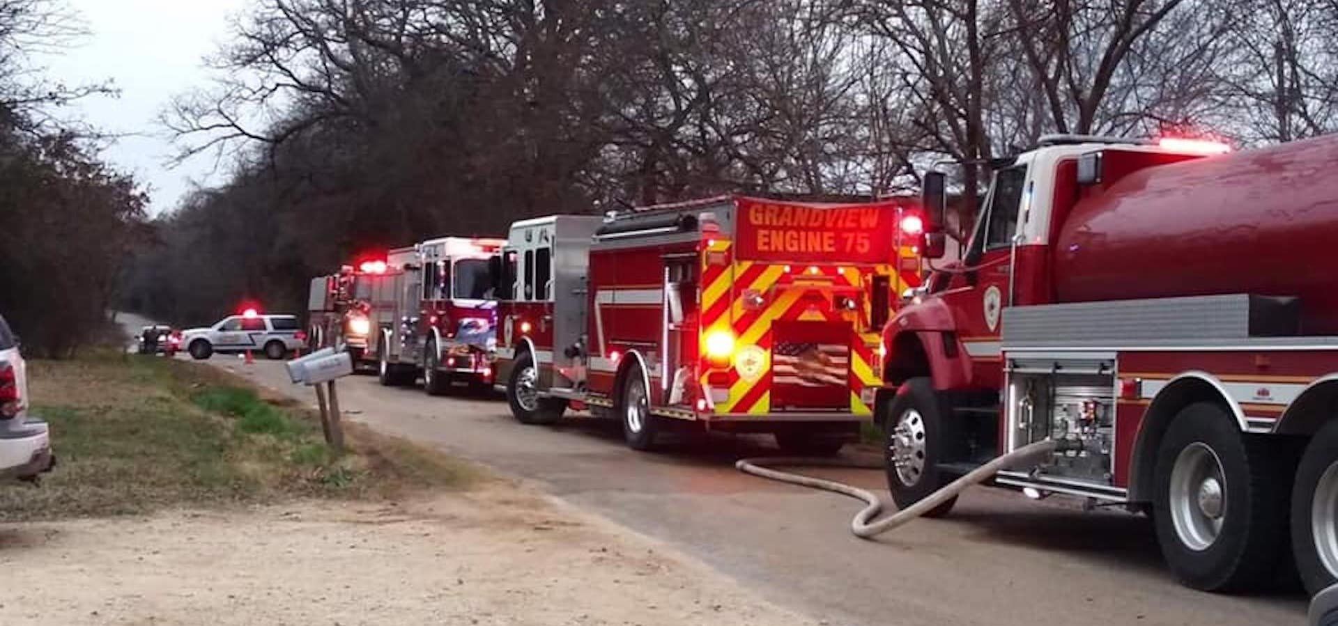 A row of fire trucks are parked on the side of the road