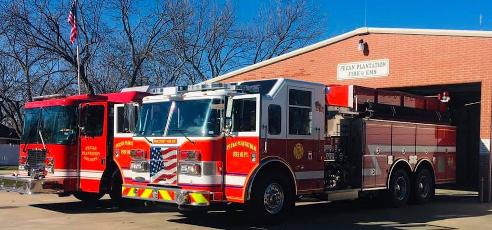 Three fire trucks are parked in front of a fire station.