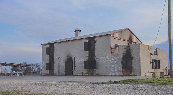 A large brick building is sitting on top of a gravel road which is the training facilities.