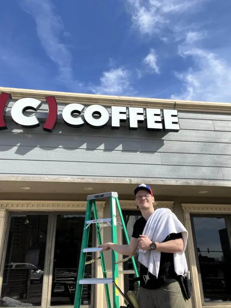 Man on ladder by a store with a
