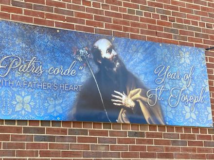 Blue banner on brick wall with a praying figure, snowflakes, and the text “Pray for our” and “Thankful Heart”