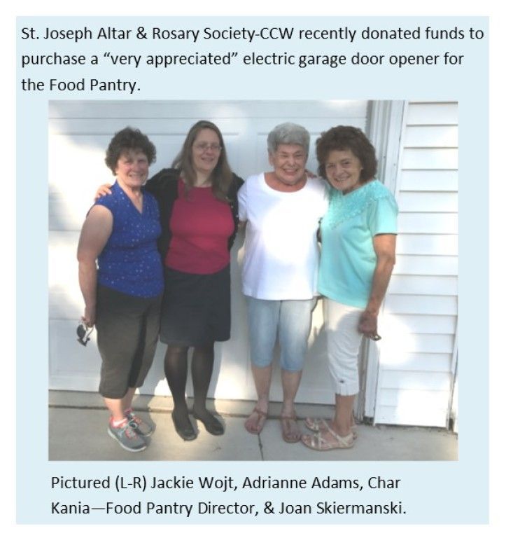 Four people pose outside a building beside a “food pantry” sign.