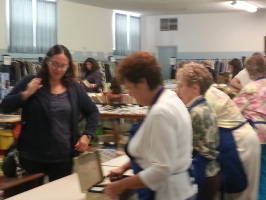 People gathered around tables in a bright room, with one woman standing by an open laptop.