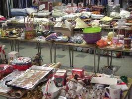 Tables covered with assorted packaged goods and household items at an indoor market stall