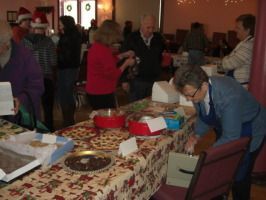 People gathered at a table with snacks and gifts in a decorated indoor party room.
