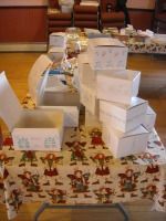 Wrapped gift boxes stacked on a patterned tablecloth in a room with wooden chairs