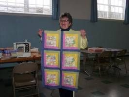 Person holding a colorful quilt in a classroom or community room