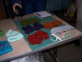 Table with colorful yarn or fabric pieces and a notebook, with a person standing beside it