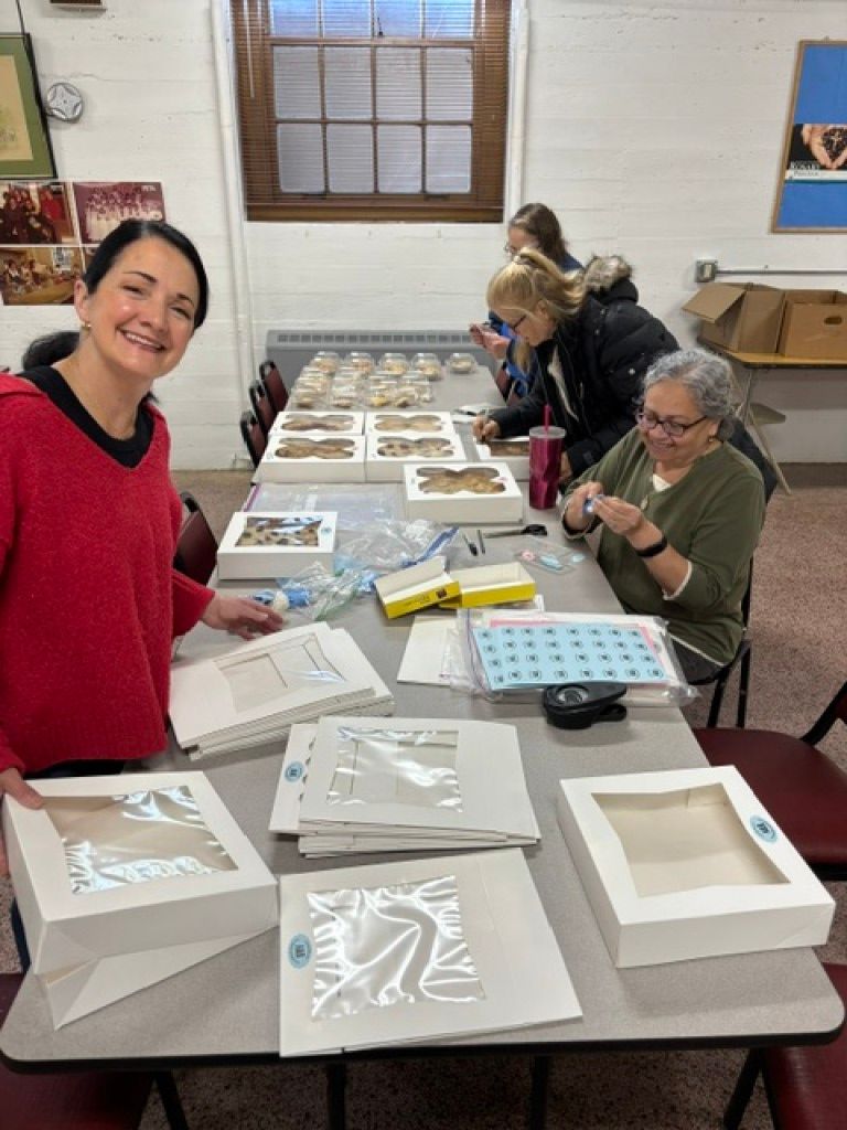 People crafting at a table with paper and framed art in a bright workshop room