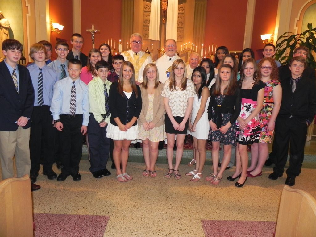 Group of teens and adults posing in a church interior, dressed in formal attire.