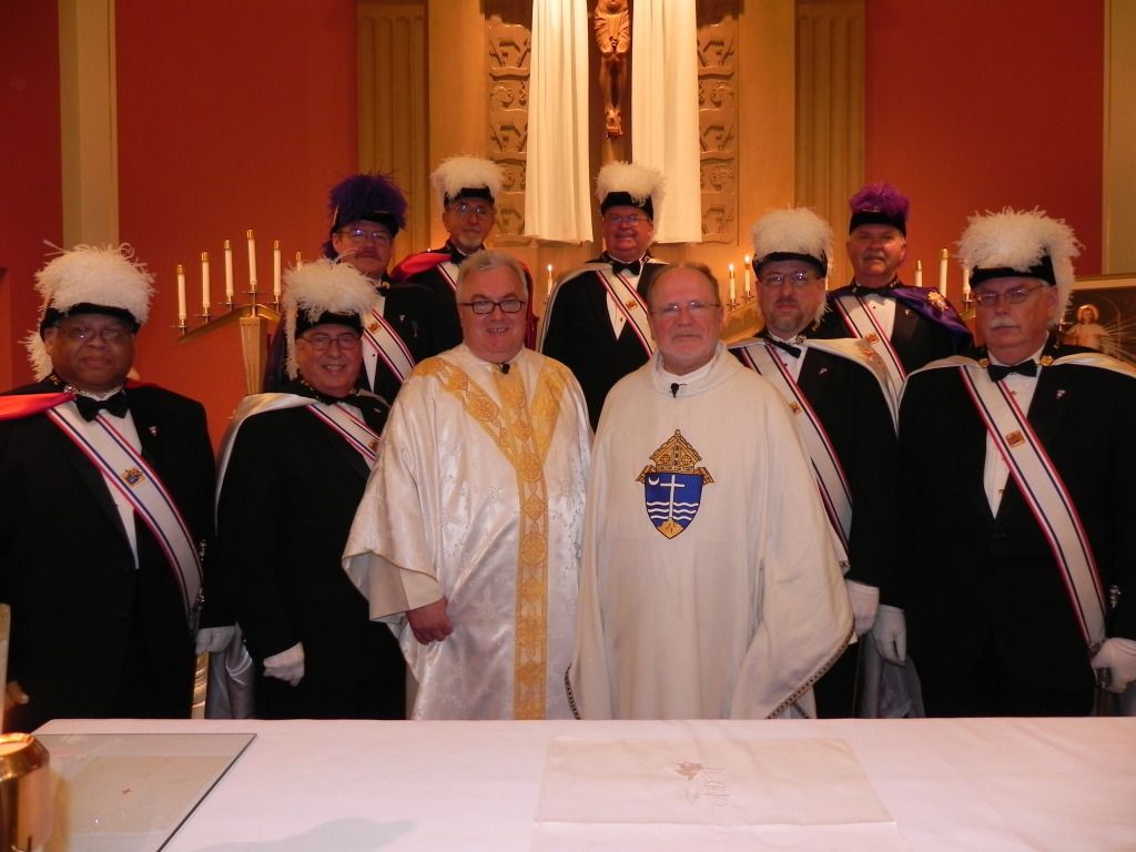 Clergy and knights pose in ceremonial robes inside a church, with candles and a gold altar backdrop.