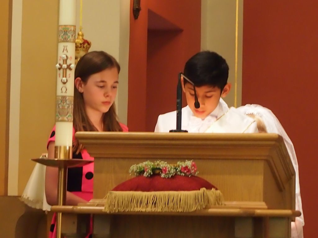 Two people reading at a church lectern beside a lit candle during a service
