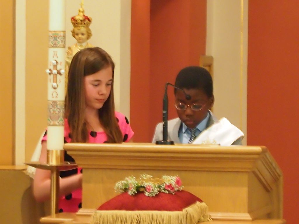Two children stand at a church lectern, reading with a microphone beside them.
