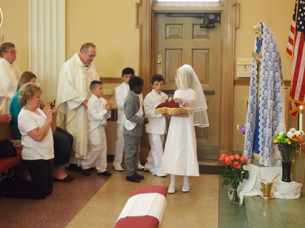 Wedding ceremony in a church, with bride and groom facing a priest and guests along the aisle.