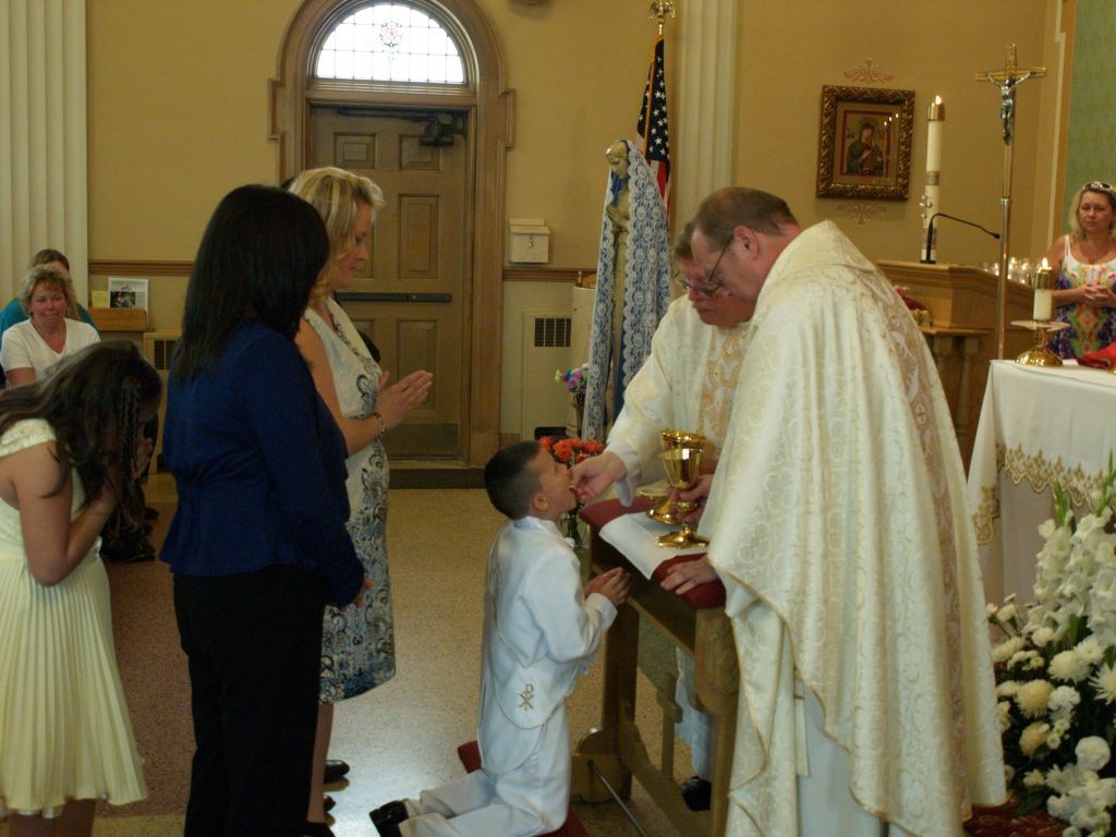 Child receiving communion from priest in a church during a ceremony