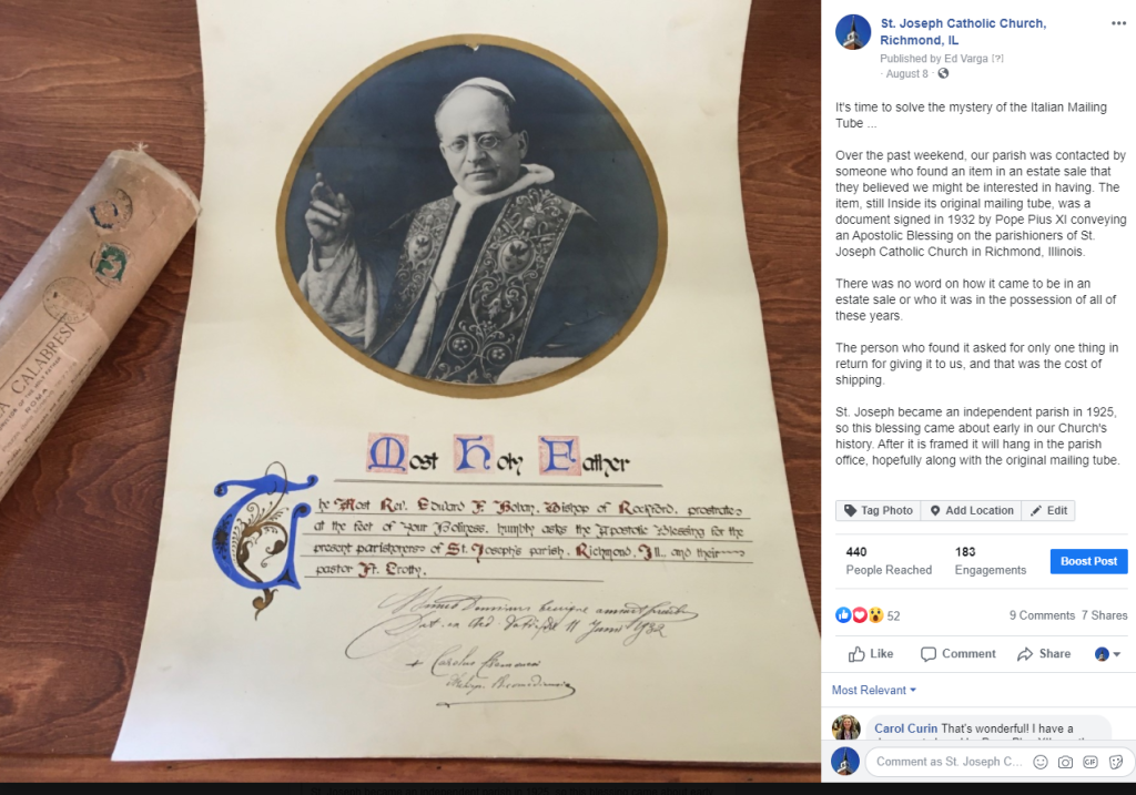 Framed certificate with a circular portrait at top and a rolled document beside it on a wooden table