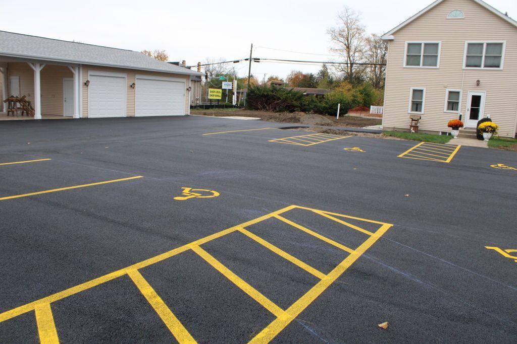 Empty parking lot with yellow painted lines beside garages and a building.