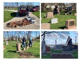 People cleaning a cemetery, raking leaves and clearing debris among gravestones