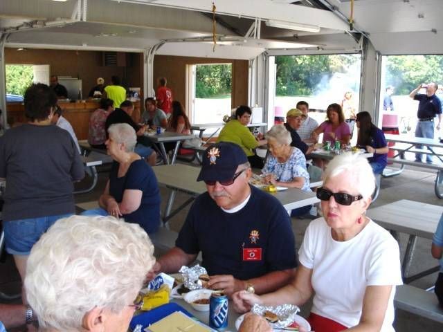 People eating at picnic tables in an open-air pavilion