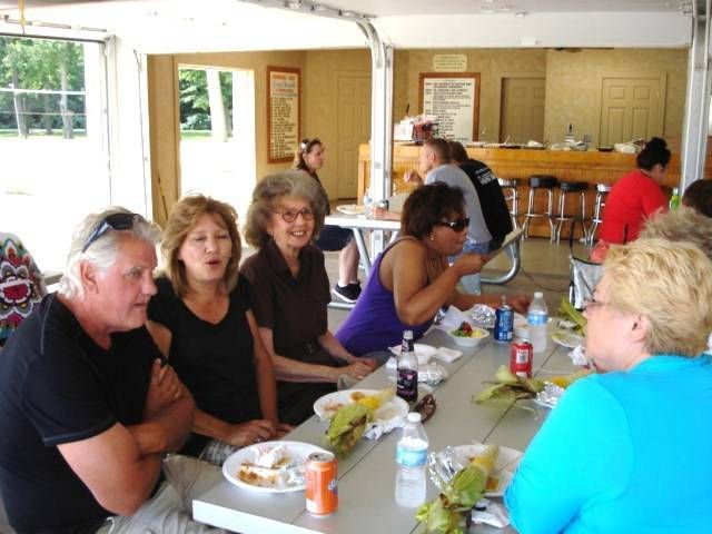 People seated at a picnic table in a bright, open dining hall, talking and eating together