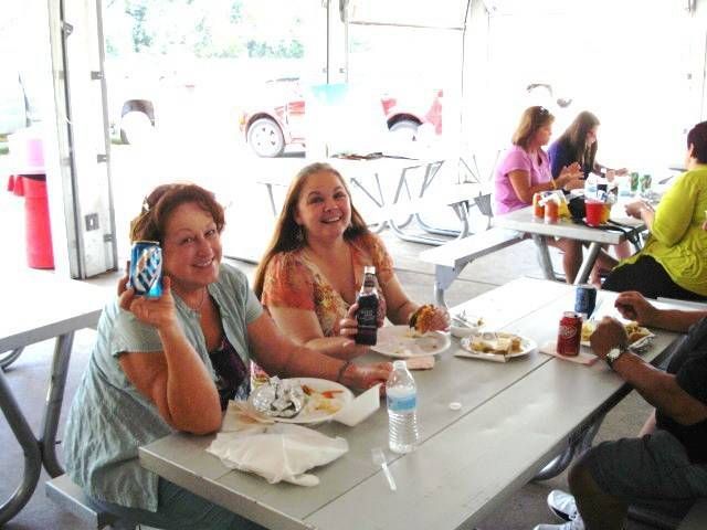 People seated at a cafeteria table eating and talking, with drinks and plates in front of them.