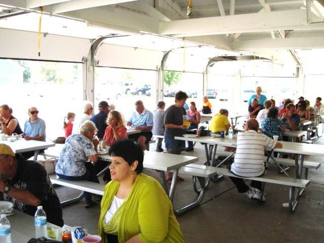 People seated at long picnic tables inside a large white event tent