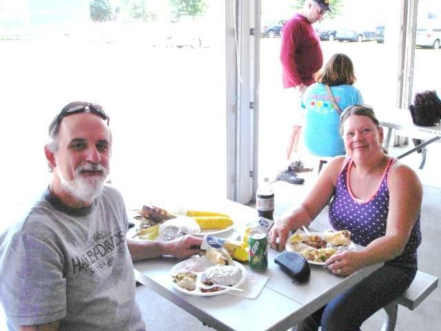 People seated at a picnic table with plates of food in a bright, casual dining area