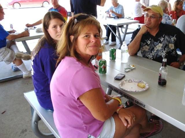 Two people seated at a picnic table, looking toward the camera in a casual outdoor dining area.