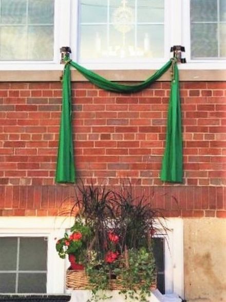 Green draped garland over a brick building window above a flower box on the ledge
