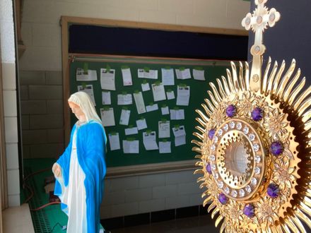 Religious display with a statue in blue and white beside a bulletin board covered in notes