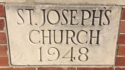 Stone plaque reading “St. Joseph’s Church 1948” set in a brick wall.