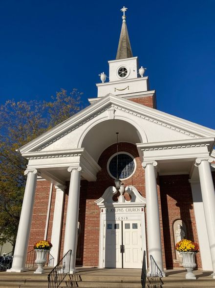 White church with columns, steeple, and brick facade under a clear blue sky