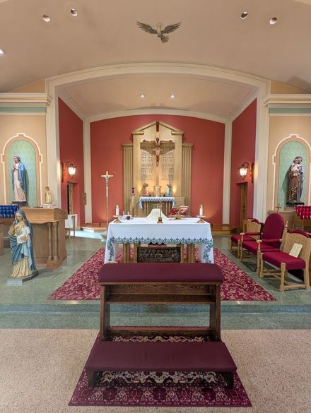 Church altar with red walls, white tablecloth, candles, and a central crucifix in a small chapel