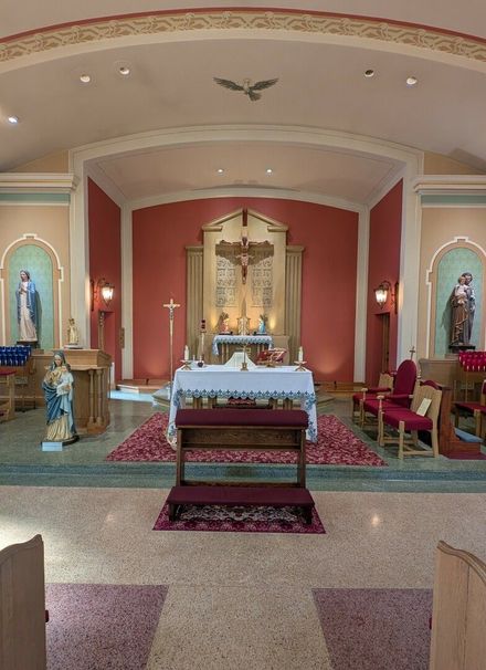 Church altar with white cloth, red walls, statues in alcoves, and ornate gold tabernacle
