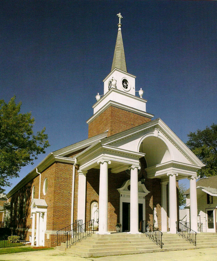 White church with tall steeple and columned porch against a blue sky