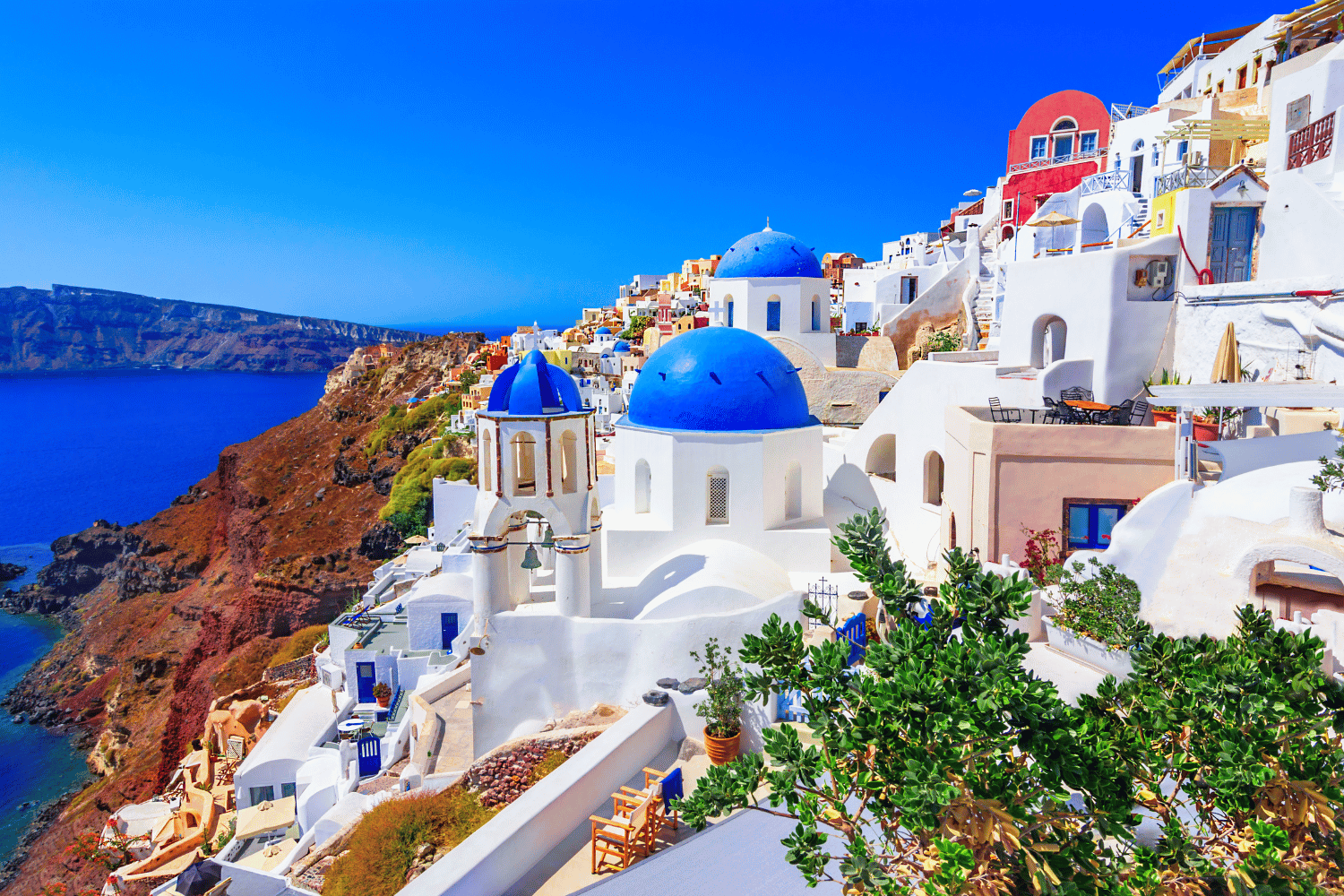 White and blue cliffside buildings overlooking a deep blue sea under a clear sky.