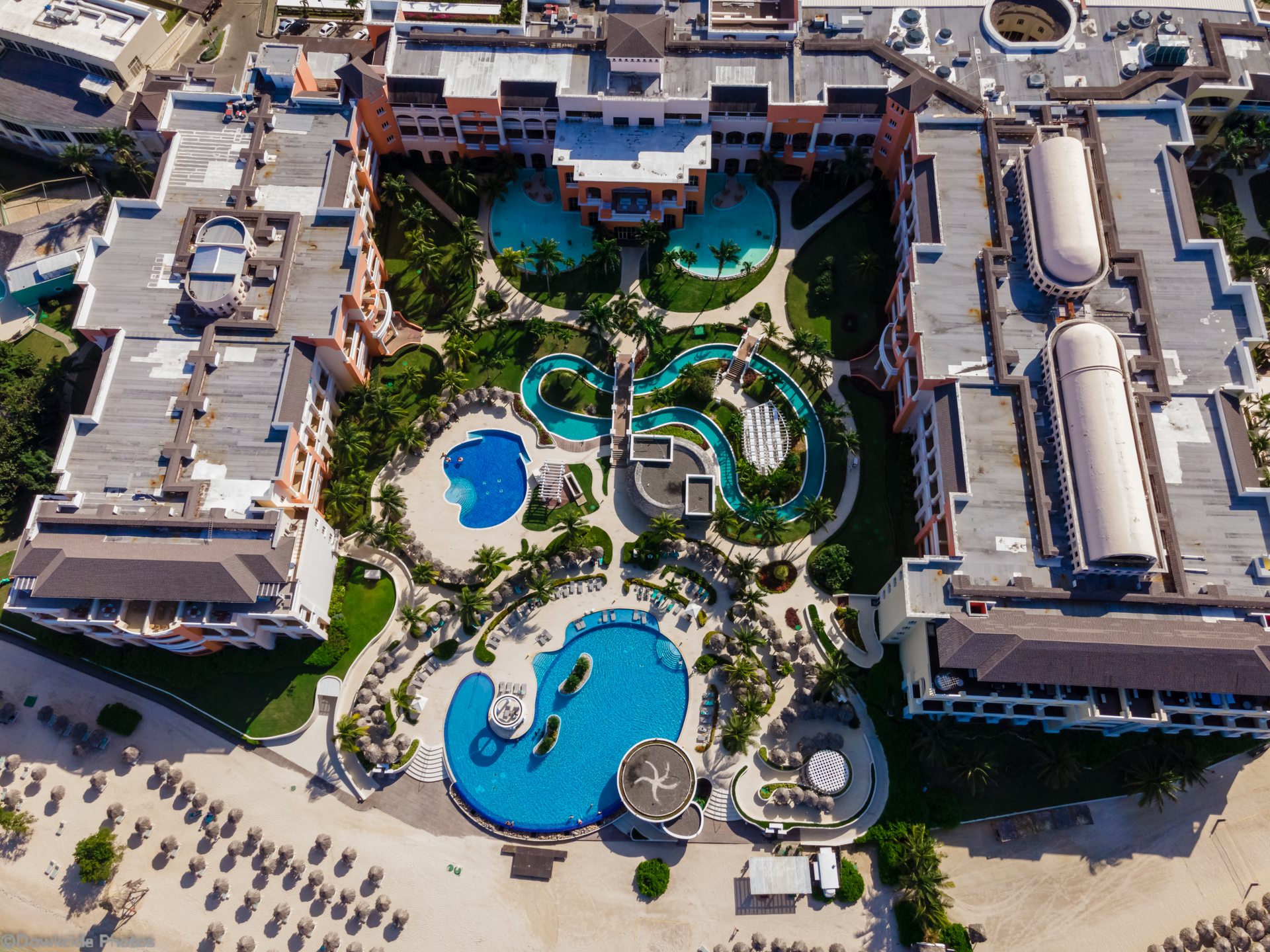 Aerial view of a hotel resort with blue pools, winding water slides, and sun loungers