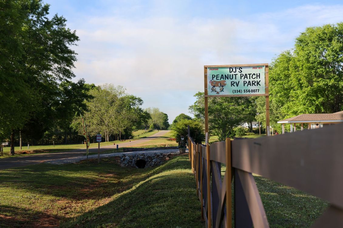 Small park path beside a canal with trees and a sign for a dog park