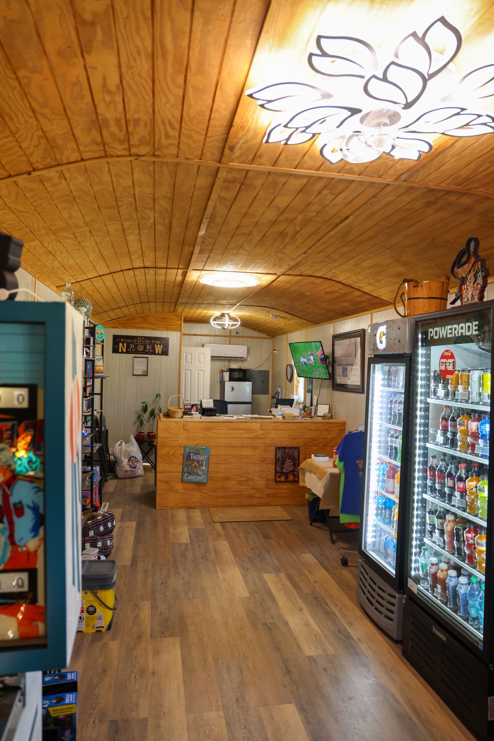 Small cozy shop interior with wooden ceiling, counter, and drink coolers along the right wall.