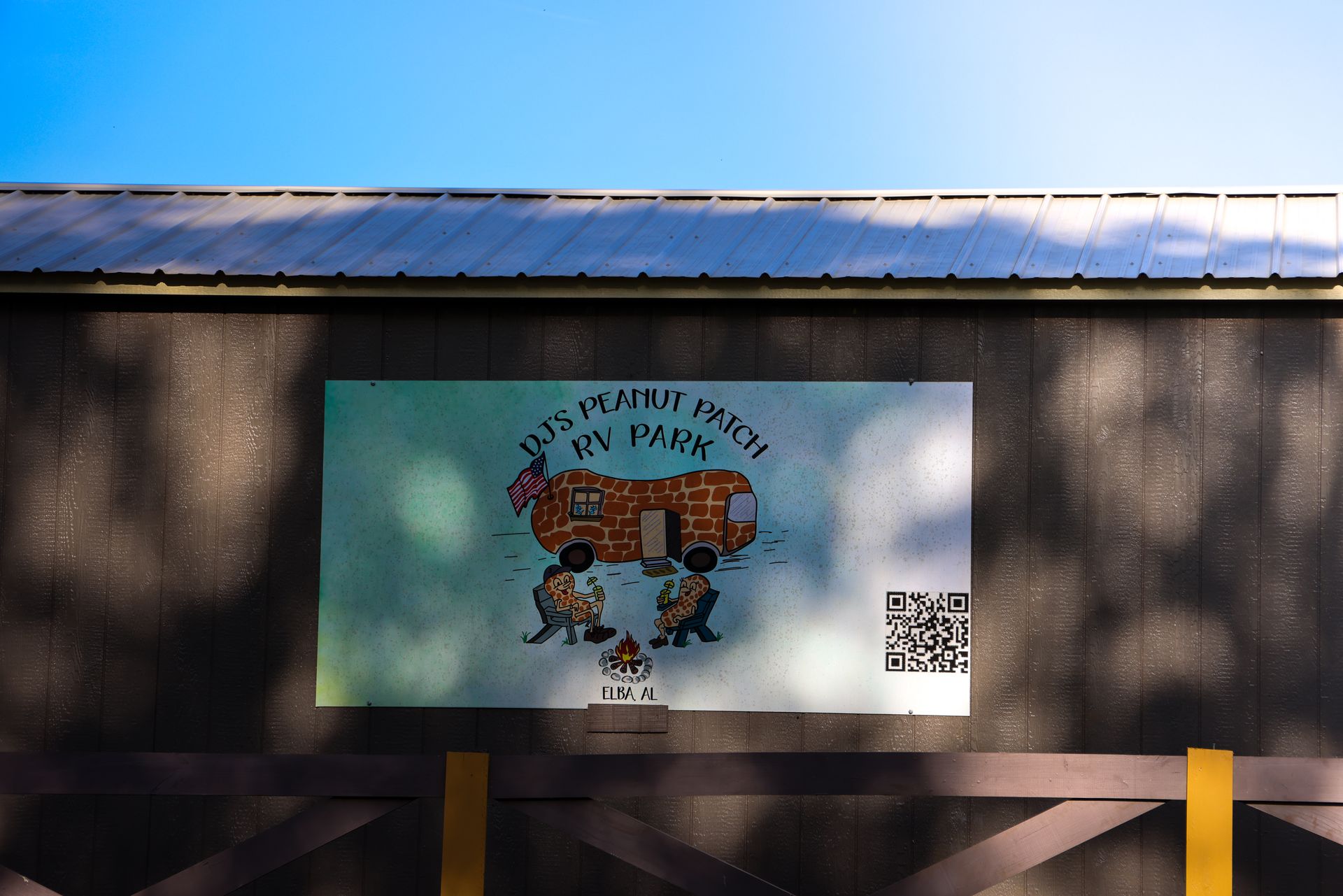 Mural on a building wall with cartoon animals and a QR code, beneath a metal roof