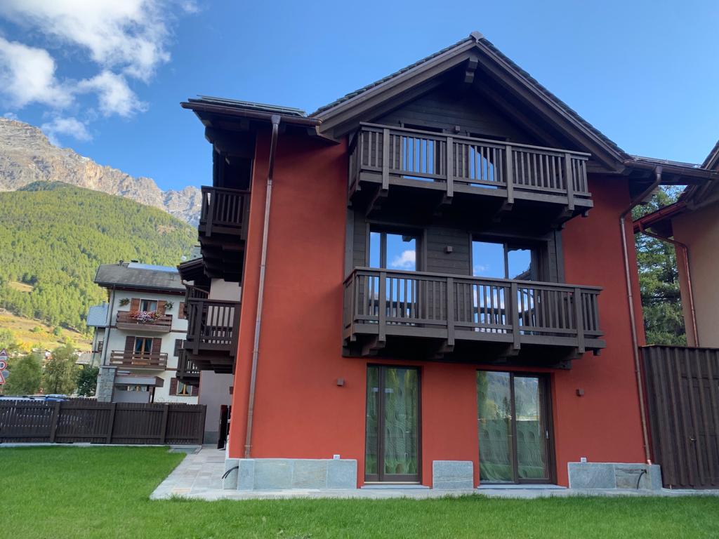 Una casa rossa con un balcone e le montagne sullo sfondo