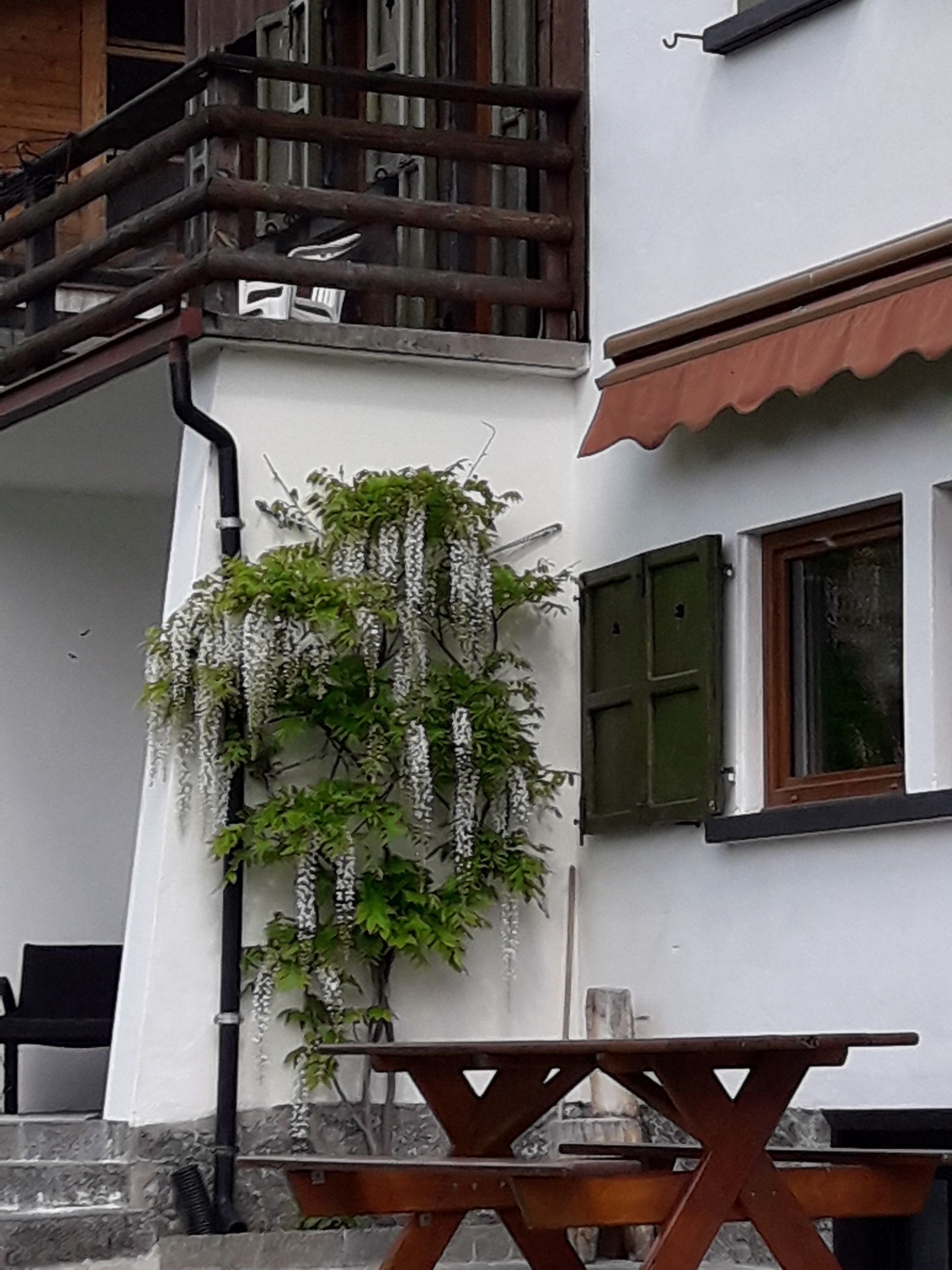 Un edificio bianco con un tavolo da picnic in legno di fronte
